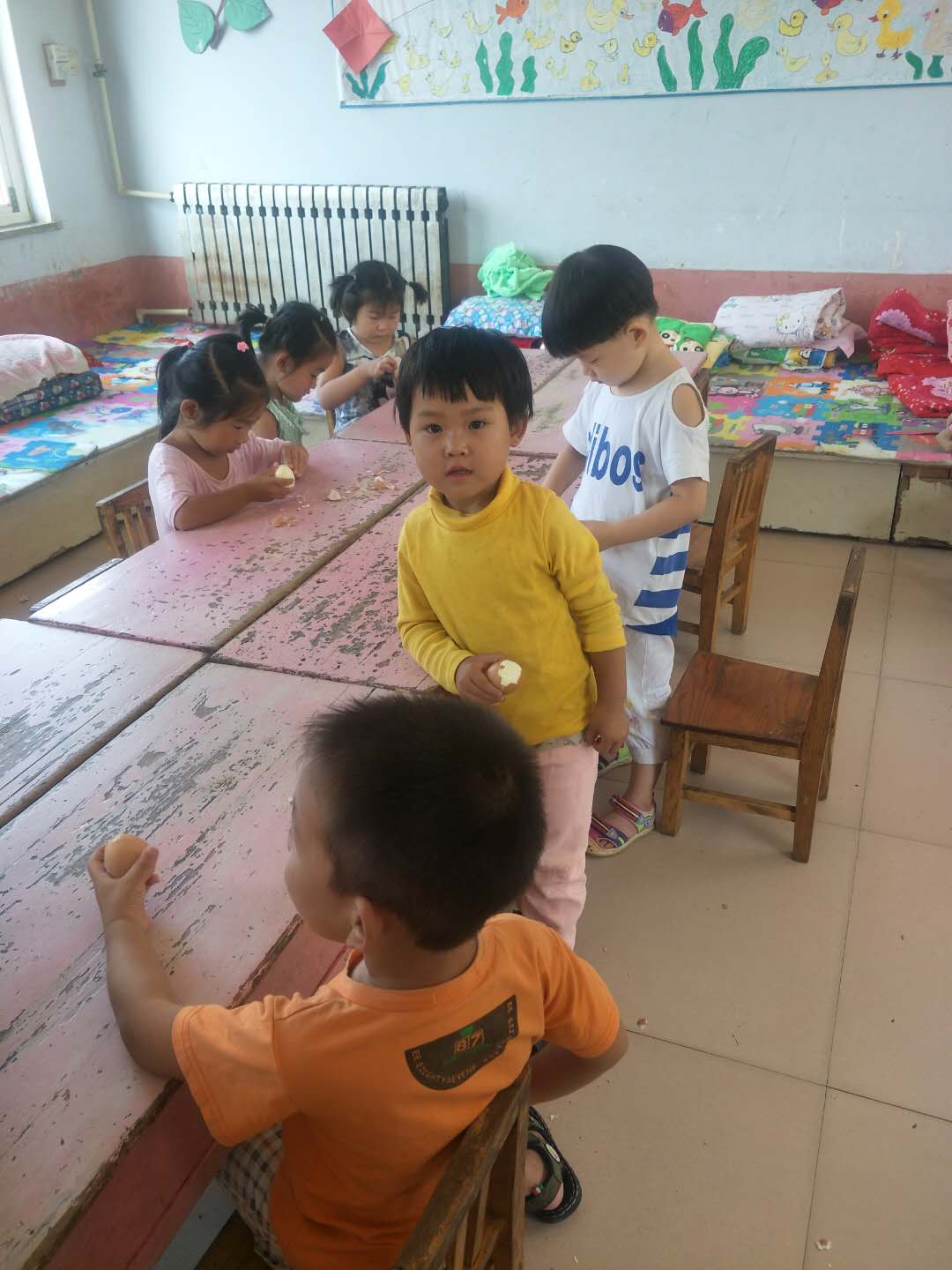 在幼儿园，与小朋友在一起的妮妮（图中穿黄色衣服的为妮妮）